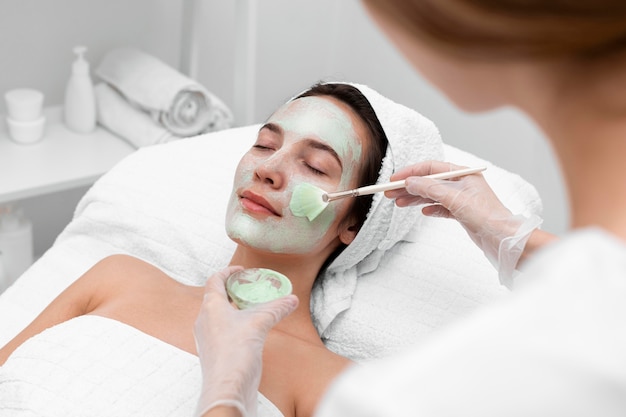 Beautician applying face mask female client